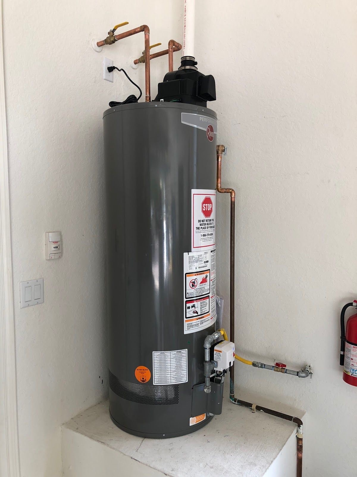 Newly installed Rheem water heater with clean copper piping and shutoff valves